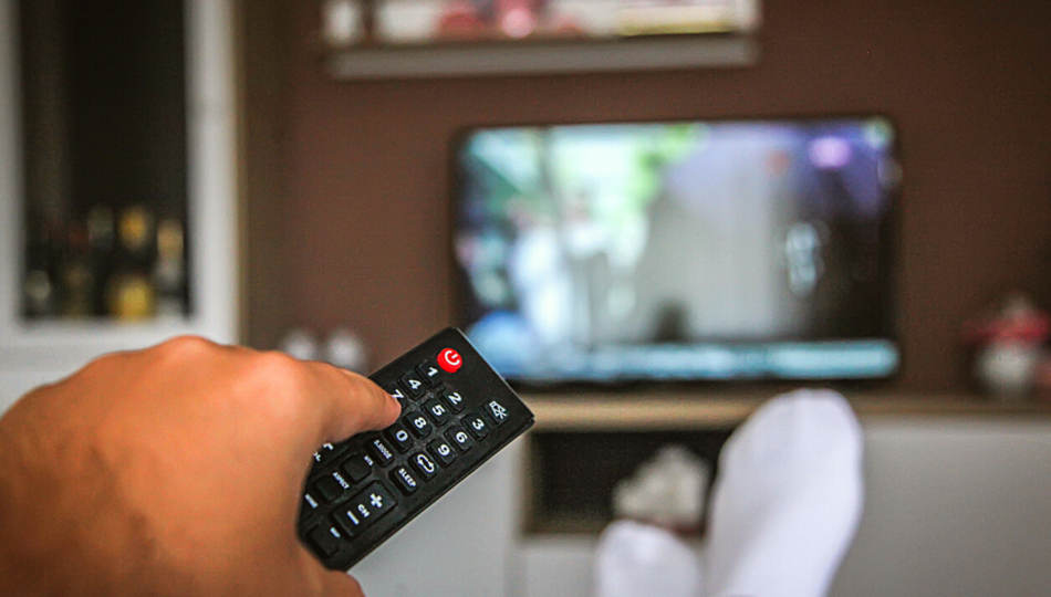 Close up of hand holding television remote and watching television